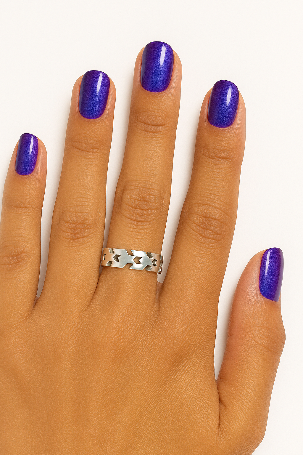 Hand with purple nail polish and a silver ring on a white background